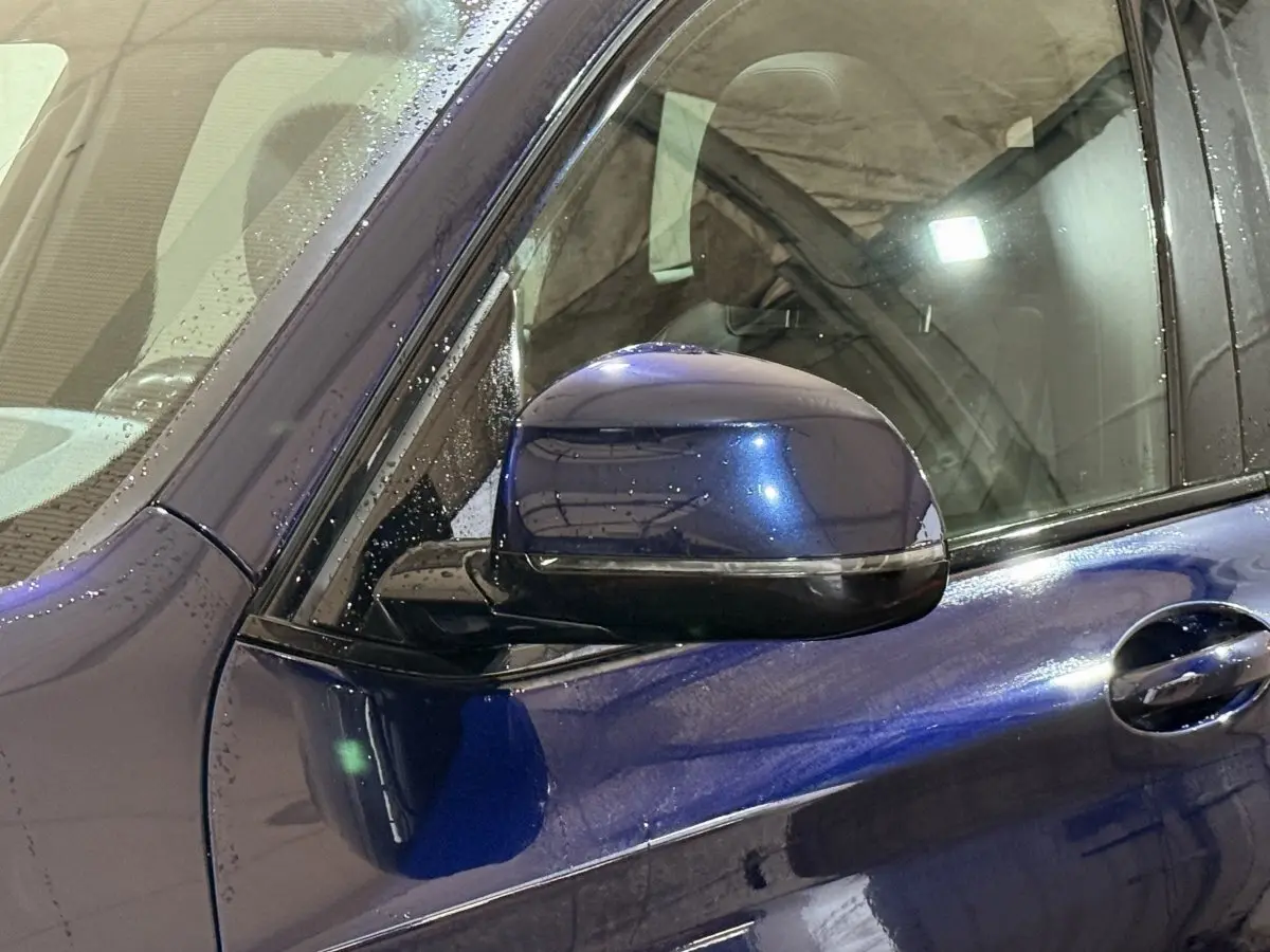 Rétroviseur côté gauche bleu métallisé d'un BMW X3 xDrive30e 2023, avec poignée de porte et vitre partielle visible.