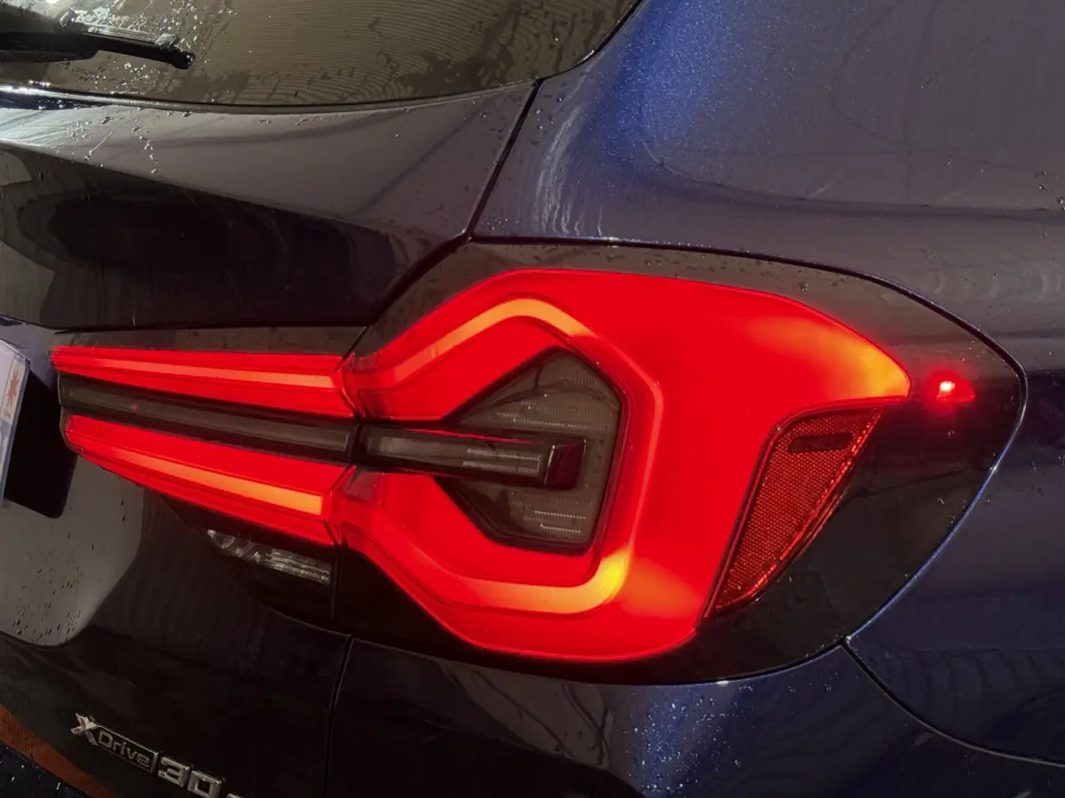 Gros plan sur le feu arrière droit rouge vif du BMW X3 xDrive30e bleu, soulignant son design lumineux distinctif.
