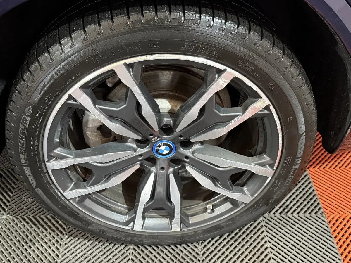 Gros plan sur la jante alliage à design complexe du BMW X3 bleu xDrive30e 2023, avec logo central BMW visible.