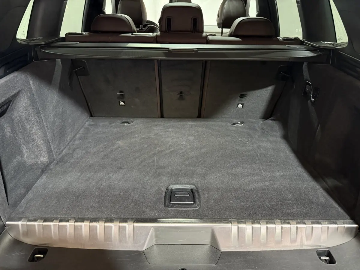 Coffre spacieux du BMW X3 xDrive30e bleu, vue arrière avec banquette arrière et cache-bagages déployé.
