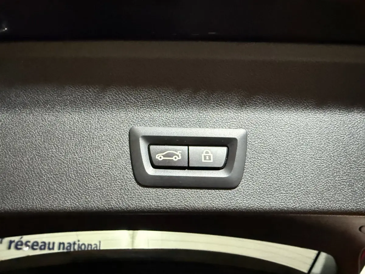 Gros plan sur les boutons d'ouverture et de verrouillage électrique du coffre du BMW X3 xDrive30e bleu 2023.