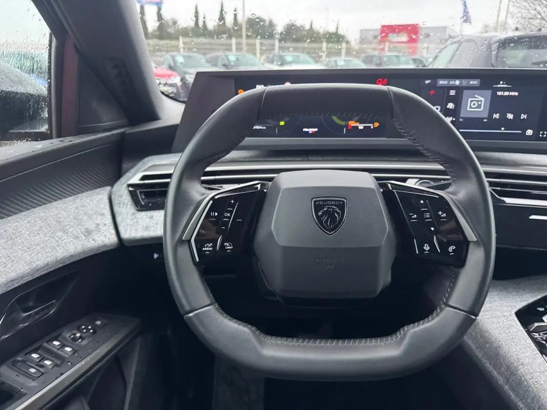 Vue intérieure centrée sur le volant cuir noir du Peugeot 3008 Hybrid 145 e-DCS6 Allure avec cockpit numérique en arrière-plan.