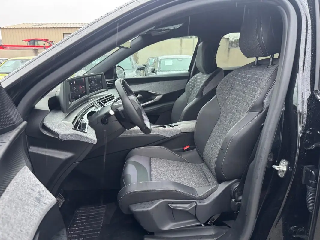 Vue intérieure côté conducteur du Peugeot 3008 Hybrid 145 e-DCS6 Allure noir, avec sièges tissu et cuir et tableau de bord numérique.