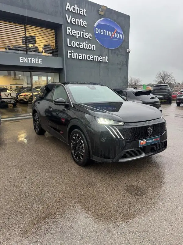 Peugeot 3008 Hybrid noir en 3/4 avant droit, feux allumés, jantes alliage 19 pouces, devant concession Distinxion.