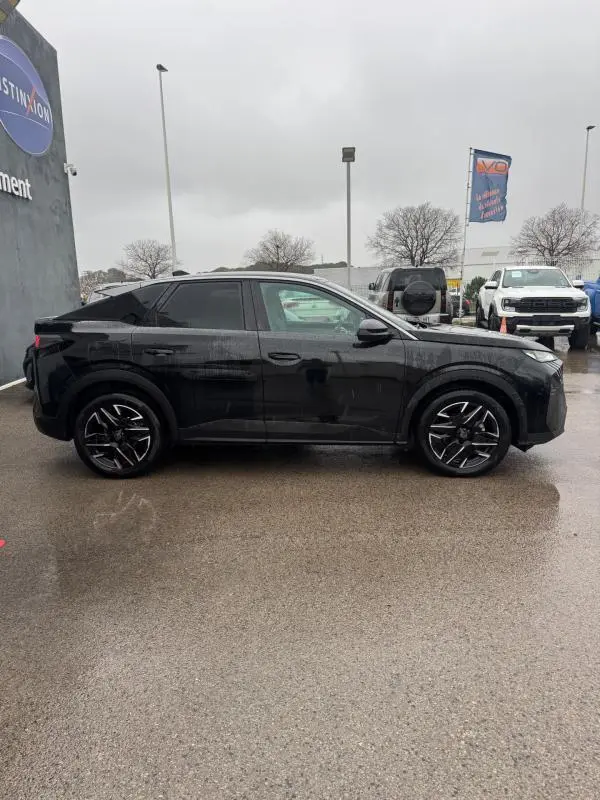 Vue de profil côté gauche d'un Peugeot 3008 Hybrid 145 Allure noir avec jantes alliage 19 pouces sous un ciel gris.