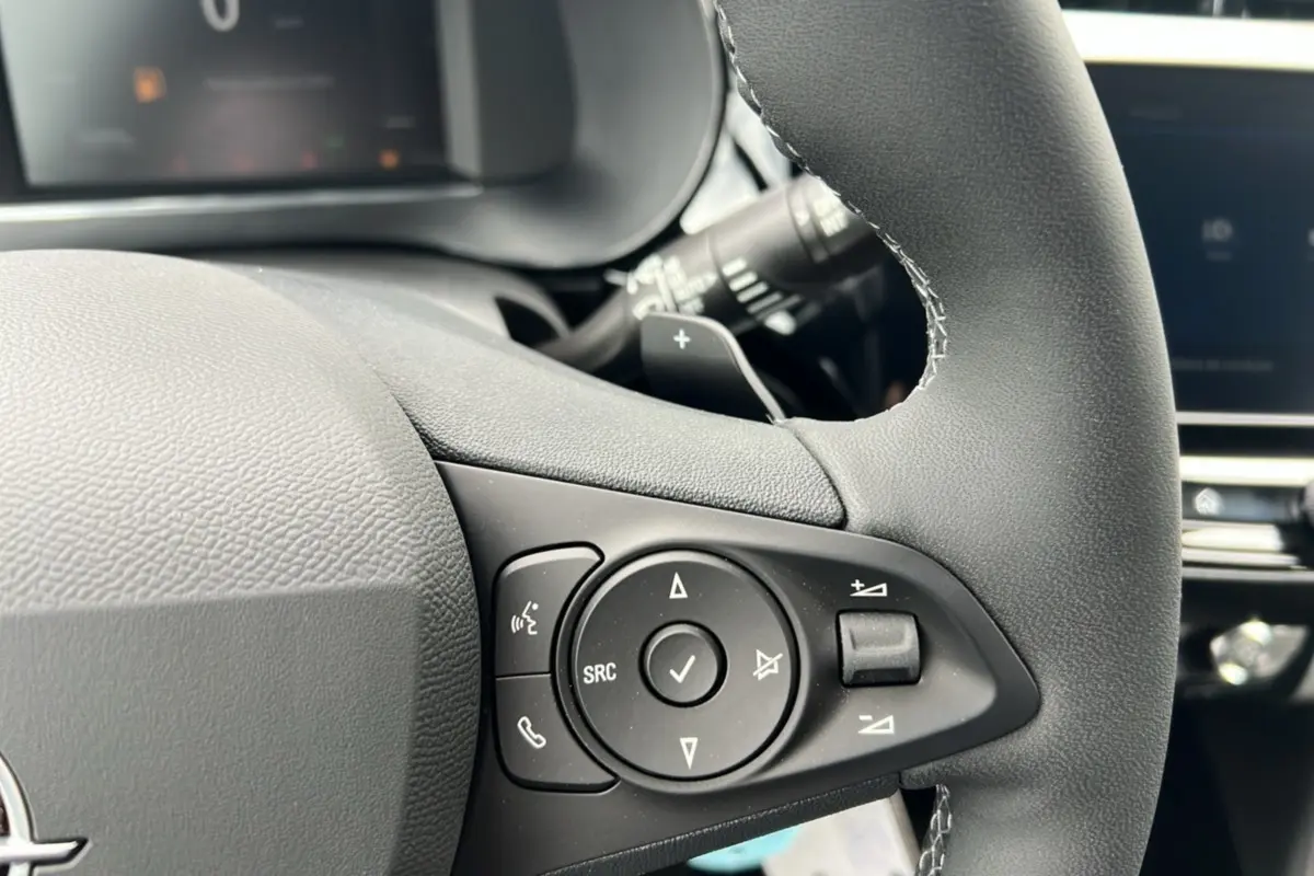 Gros plan sur les commandes multifonctions du volant cuir de l’Opel Corsa Hybrid blanc Kontur, version 2026.