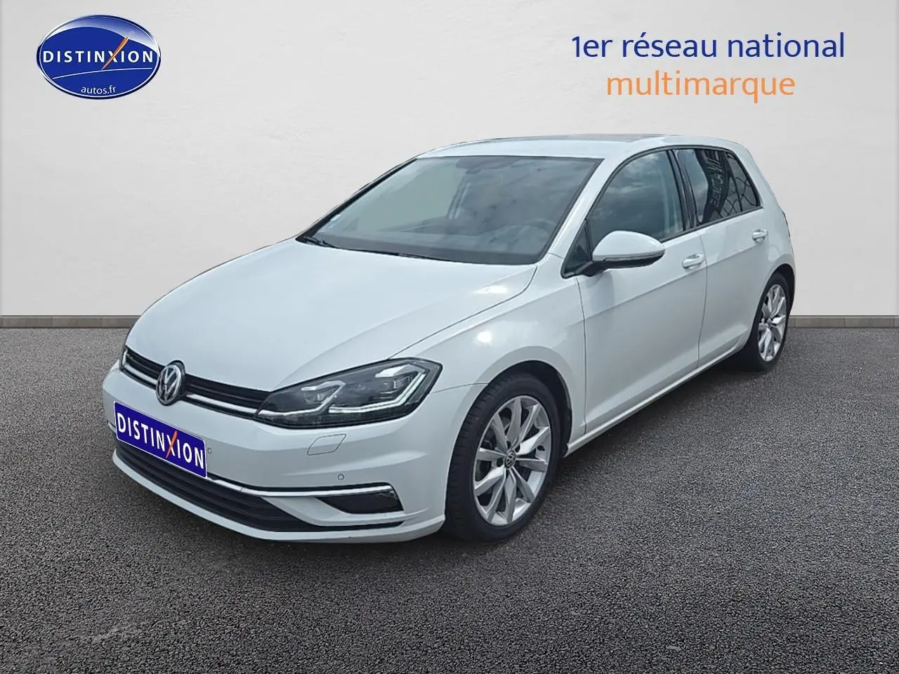 Volkswagen Golf blanche vue en 3/4 avant droit, avec jantes alu et phares LED allumés.