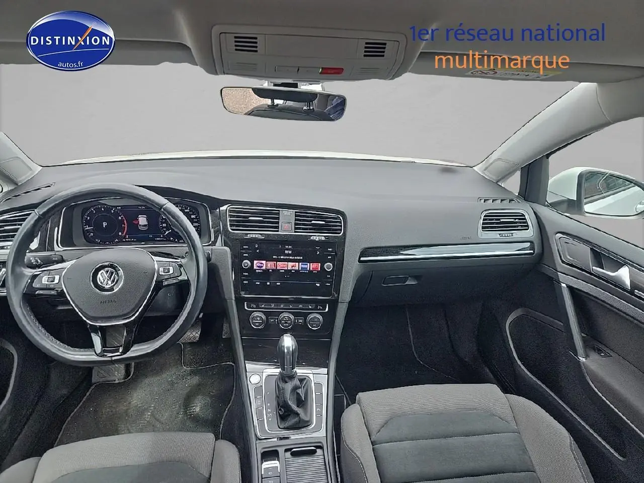 Vue intérieure avant de la Volkswagen Golf blanche 2019, tableau de bord et volant multifonction en cuir visibles.