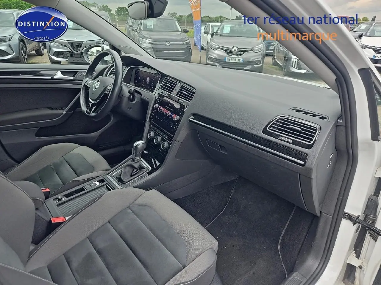 Intérieur avant droit de Volkswagen Golf blanc 2019, montrant sièges tissu et console centrale avec boîte auto.