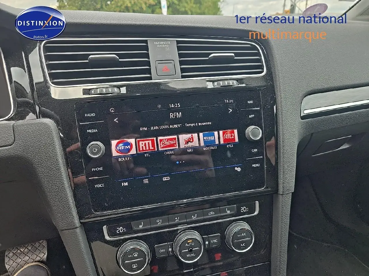 Vue rapprochée de la console centrale noire avec écran tactile et commandes de climatisation d'une Volkswagen Golf blanche.