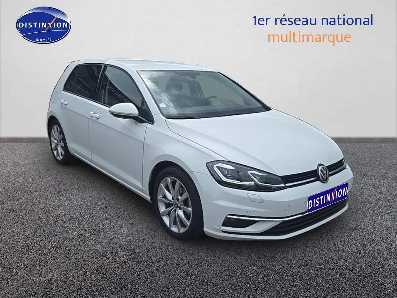 Volkswagen Golf blanc vue 3/4 avant droit avec jantes alu et phares LED allumés.