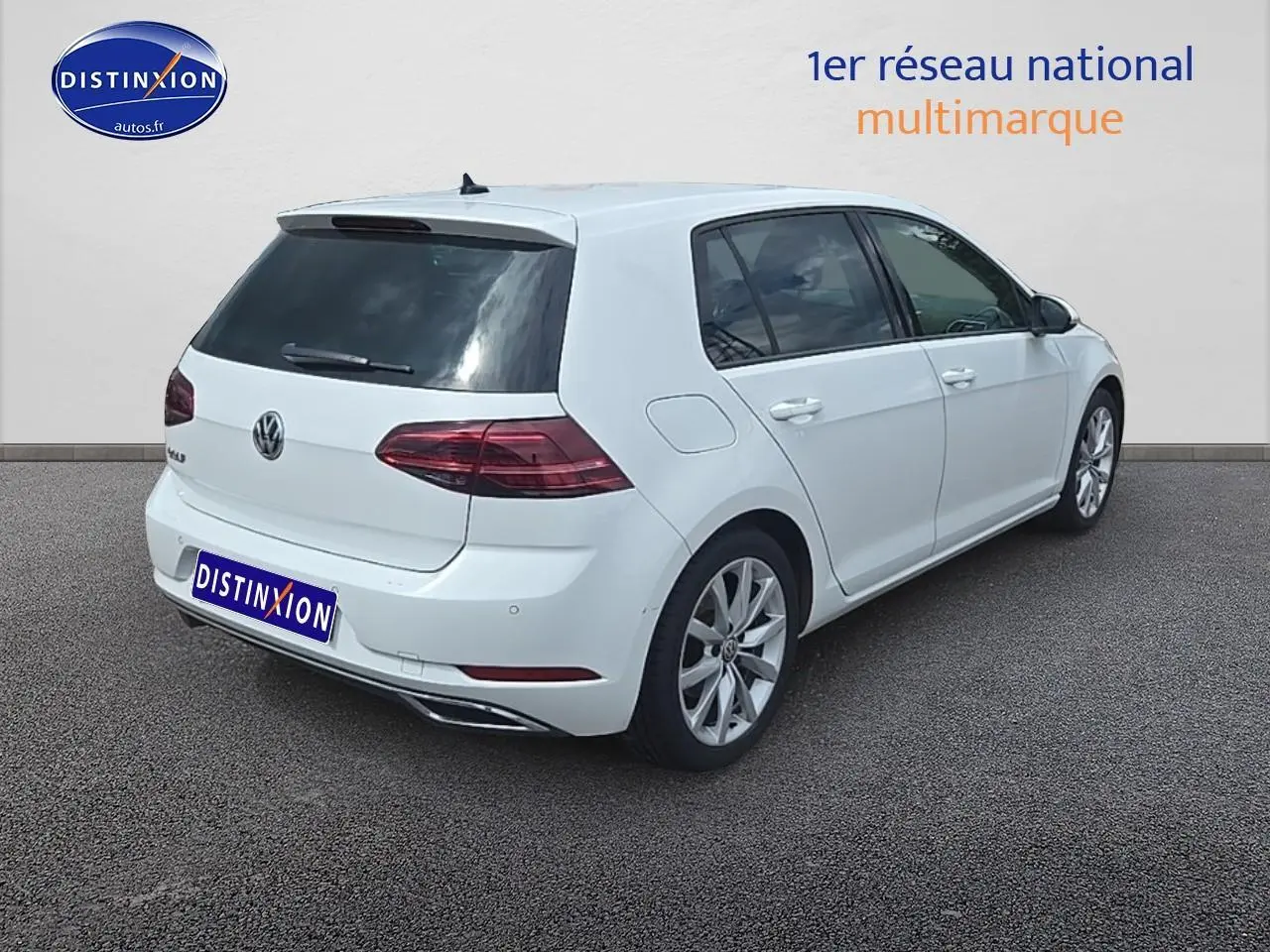 Vue 3/4 arrière droite d'une Volkswagen Golf blanche avec jantes alliage et vitres teintées.