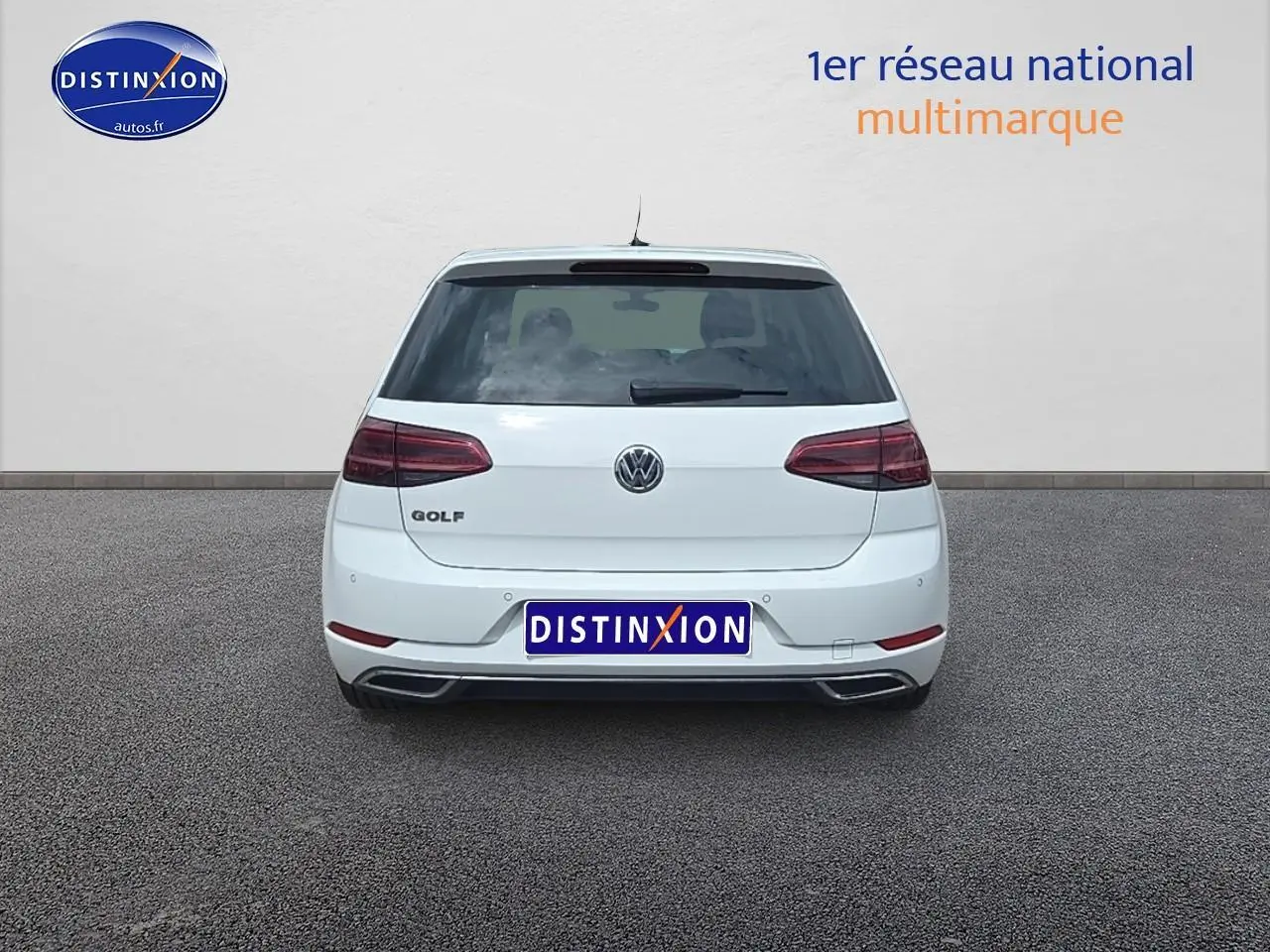 Vue arrière d'une Volkswagen Golf blanche garée sur un sol gris, avec feux arrière LED visibles.