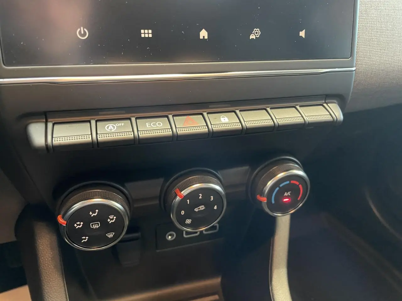 Gros plan sur les commandes de climatisation et boutons fonctionnels du tableau de bord de la Renault Clio gris Rafale.