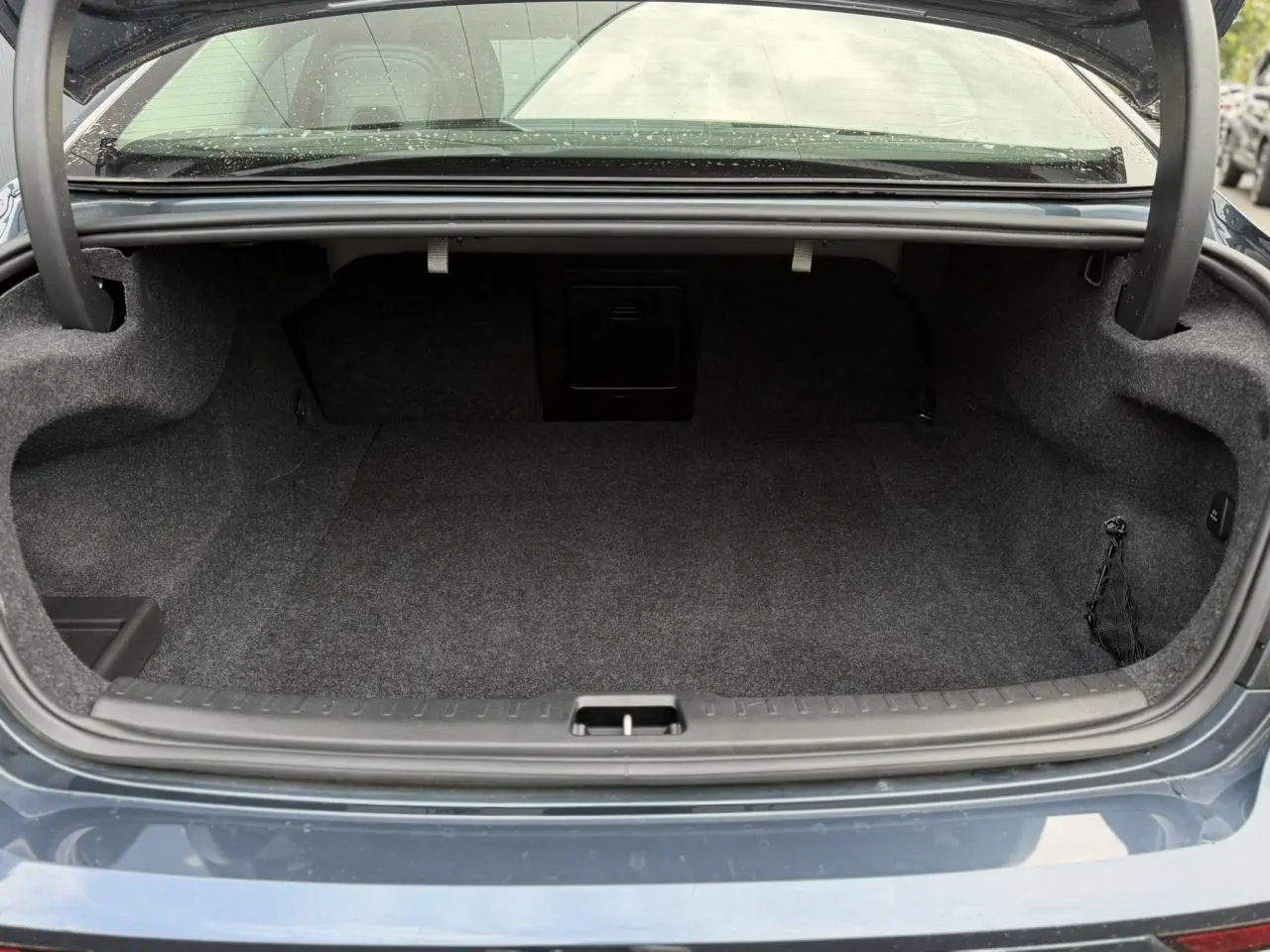 Coffre ouvert vu de l'arrière d'une Volvo S60 2024 gris Denim, montrant un espace de rangement vide et propre.