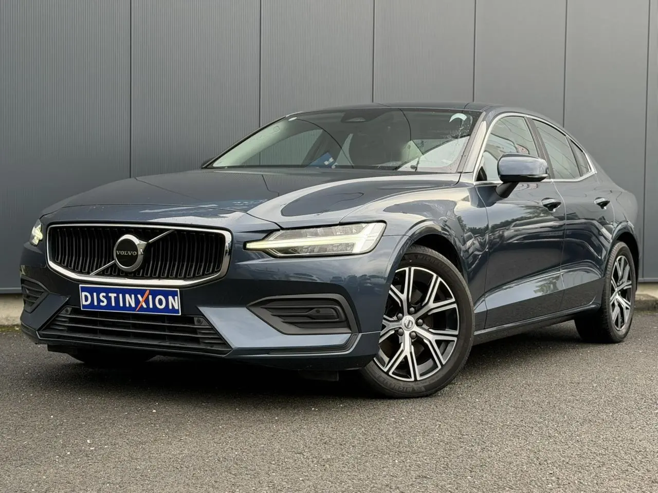 Volvo S60 B4 2024 gris Denim vue 3/4 avant avec jantes alliage 17 pouces et calandre noire chromée.