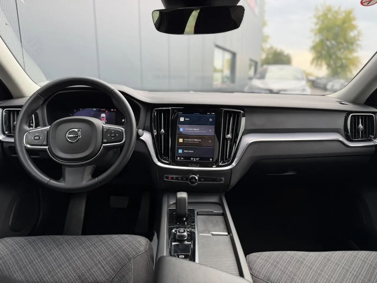 Vue intérieure avant du Volvo S60 gris Denim 2024, avec tableau de bord moderne et écran tactile central.