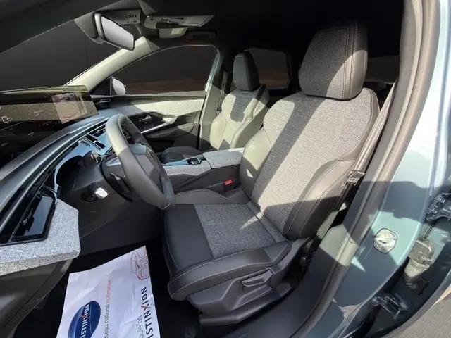 Vue intérieure côté conducteur du Peugeot 3008 hybride bleu 2026, sièges bi-matière gris et noir, tableau de bord moderne.