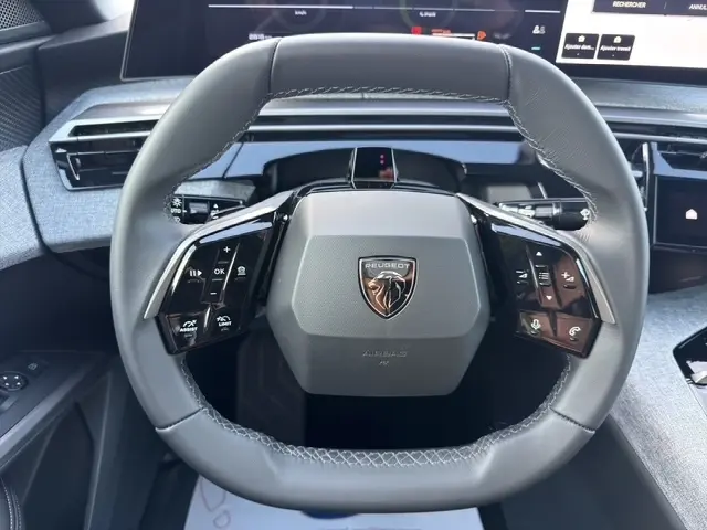 Gros plan sur le volant cuir noir du Peugeot 3008 1.2 Hybrid 145, avec commandes multifonctions intégrées.