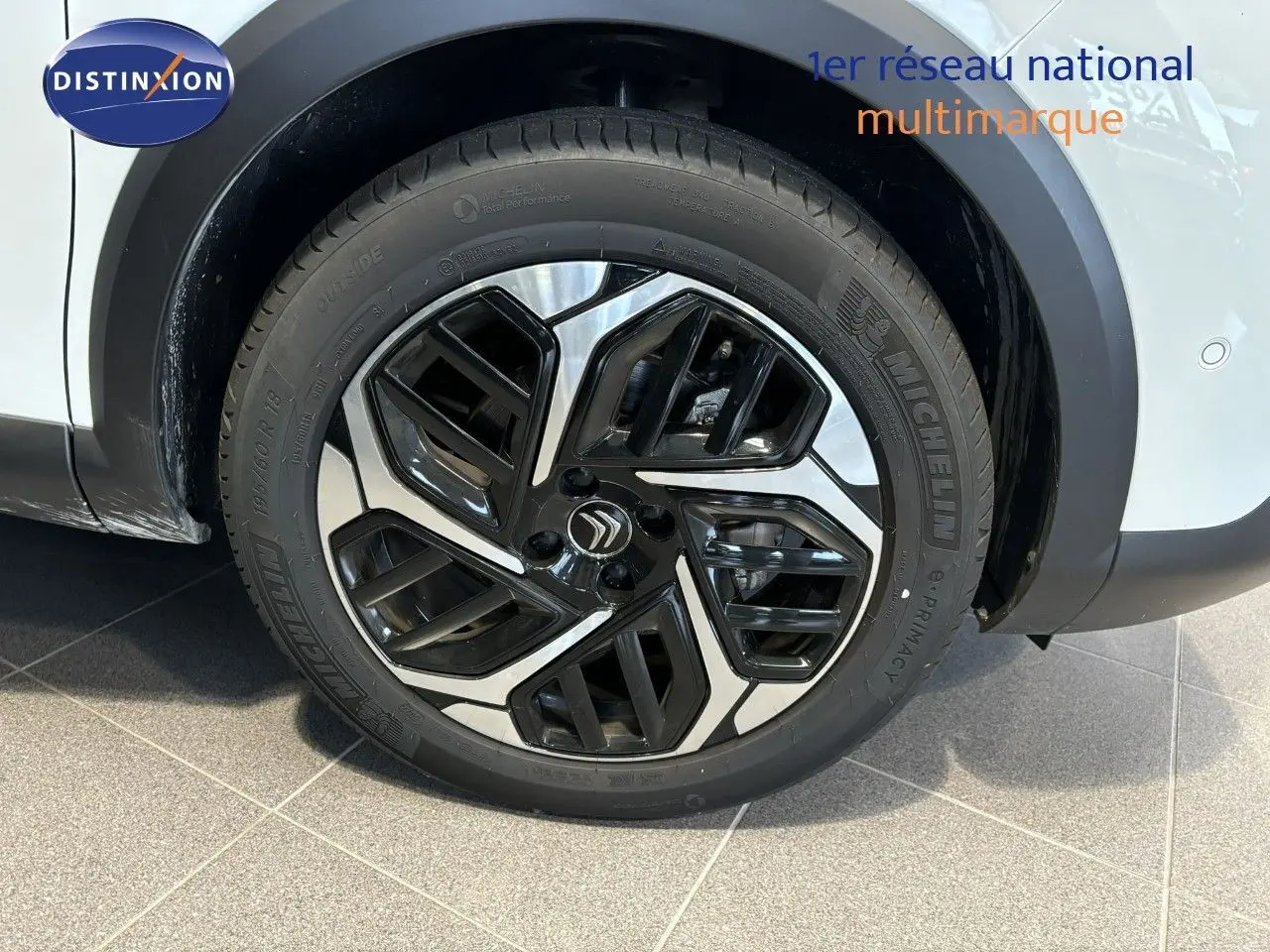 Gros plan sur la roue avant droite d'une Citroën C4 blanche 2022, mettant en valeur la jante noire et argentée au design moderne.