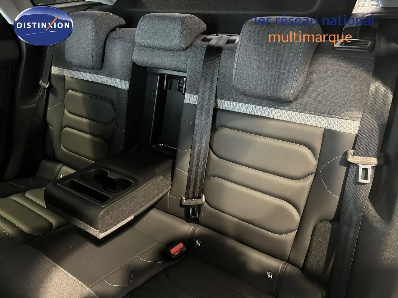 Vue intérieure arrière des sièges en tissu et cuir noir du Citroën C4 2022 avec accoudoir central relevé et ceintures visibles.