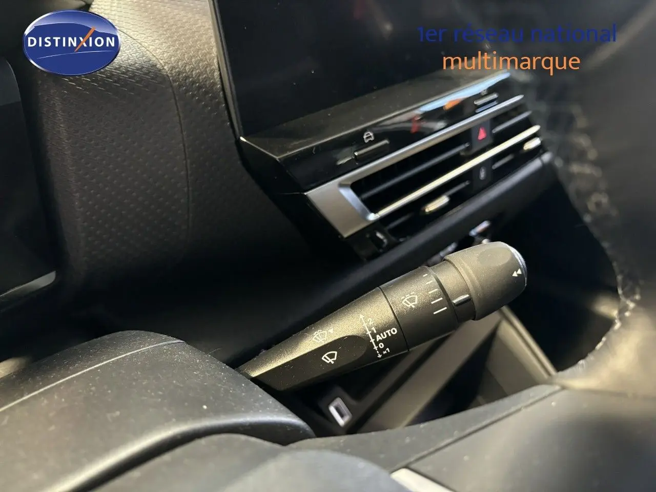 Détail du commodo d'essuie-glace dans l'habitacle du Citroën C4 blanc, avec tableau de bord et écran tactile en arrière-plan.