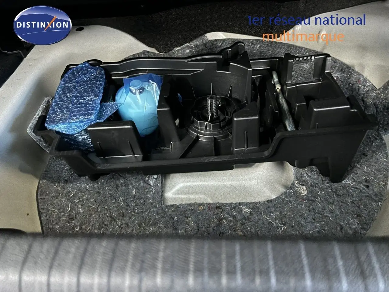 Coffret d'outils et accessoires dans le coffre d'une Citroën C4 blanche, vue plongeante sur le rangement arrière.