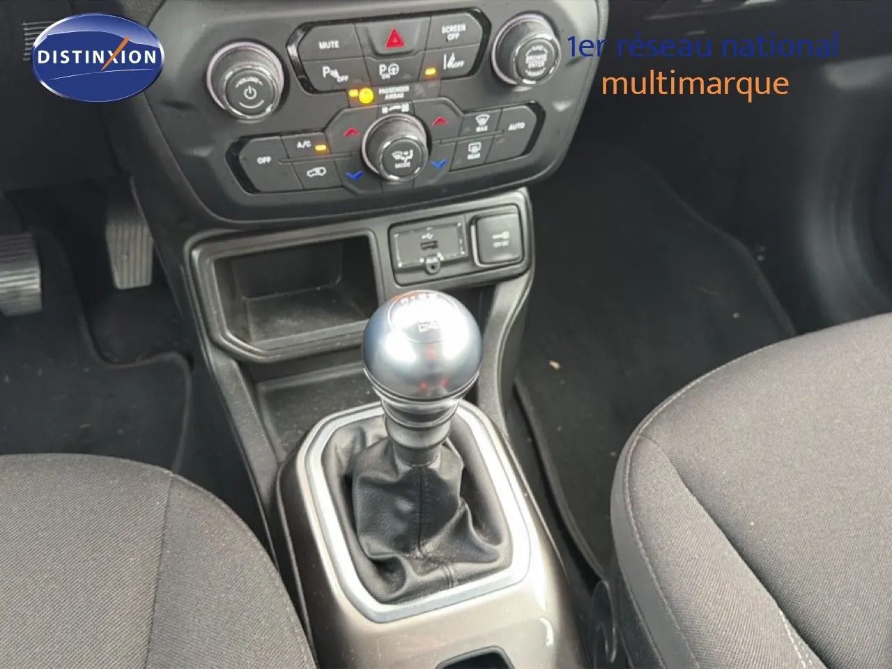 Le levier de vitesses manuel au centre de la console d'une Jeep Renegade noire, avec commandes de climatisation visibles.