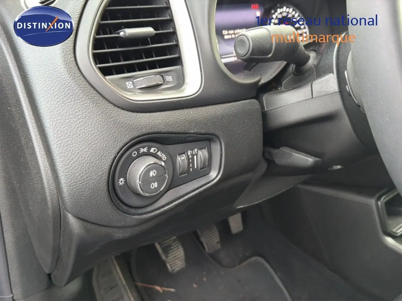 Détail du tableau de bord côté gauche du Jeep Renegade noir 2022, avec commandes d'éclairage et pédales visibles.