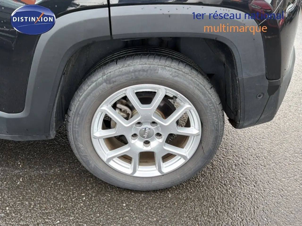 Gros plan sur la roue arrière gauche d'un Jeep Renegade noir 2022 avec jante alu argentée et logo Jeep au centre.