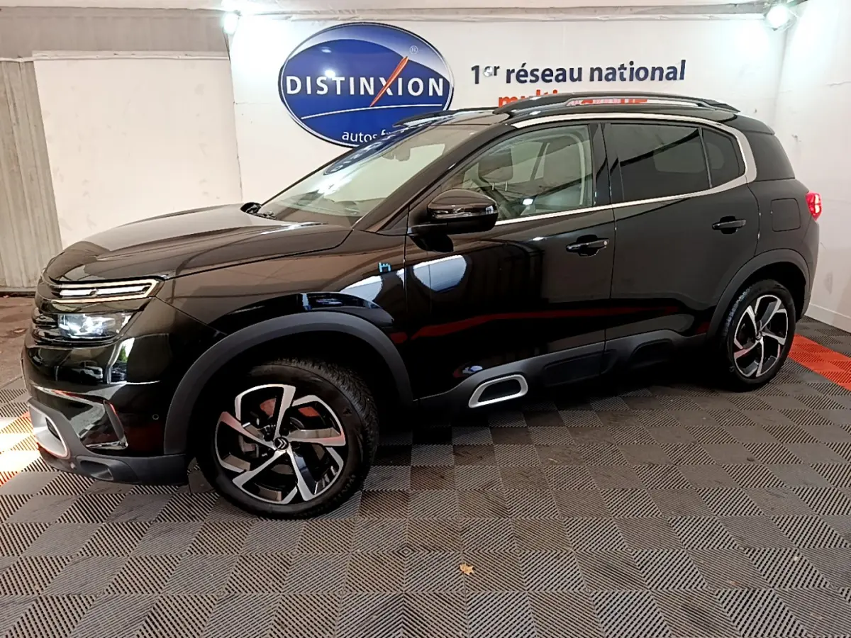 Vue de profil côté gauche d'un Citroën C5 Aircross Hybrid noir avec jantes alliage et barres de toit chromées.