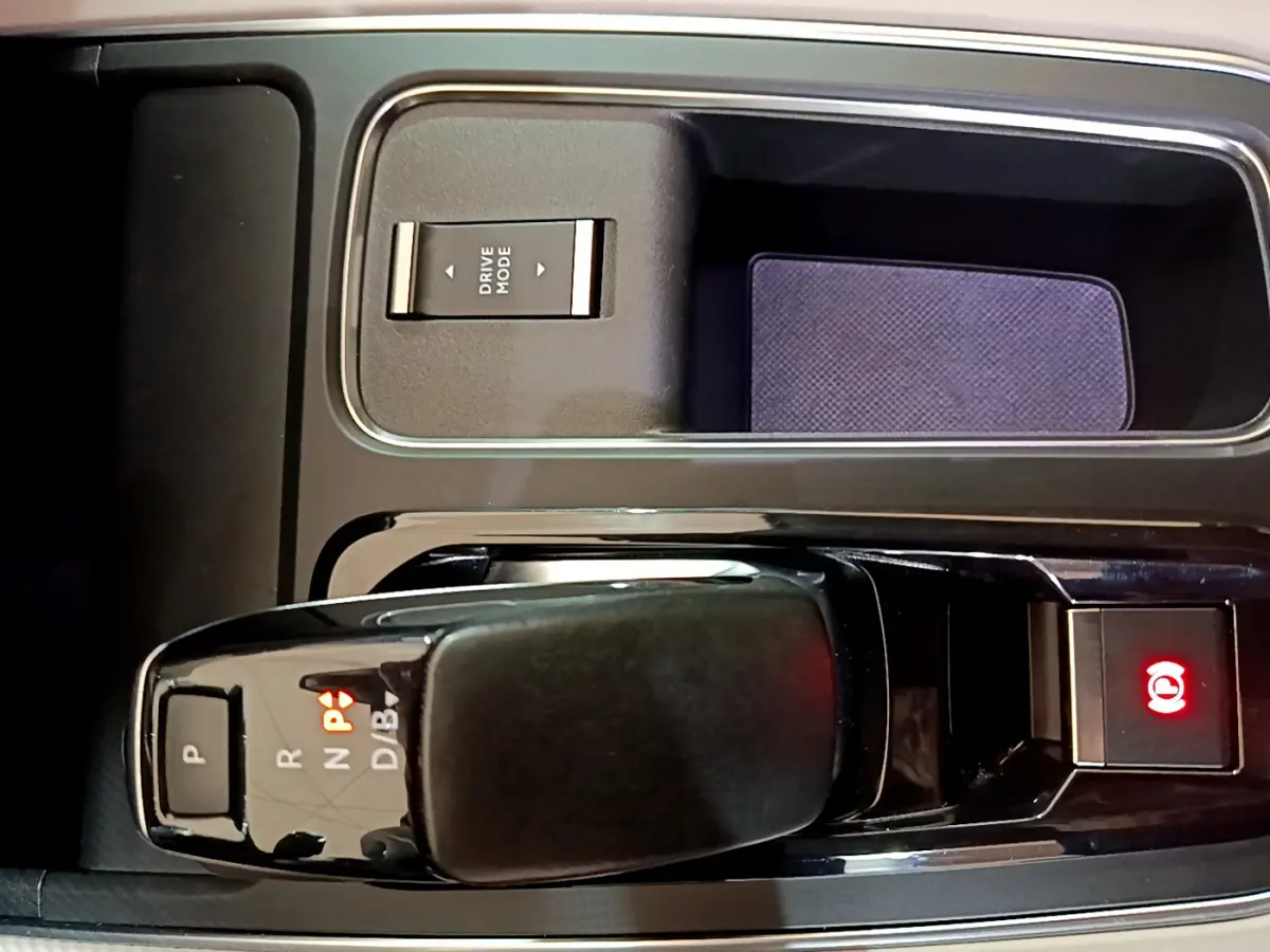 Gros plan sur la console centrale noire du Citroën C5 Aircross Hybrid 225 ë-EAT8 Shine avec levier de vitesses et bouton frein électrique allumé.