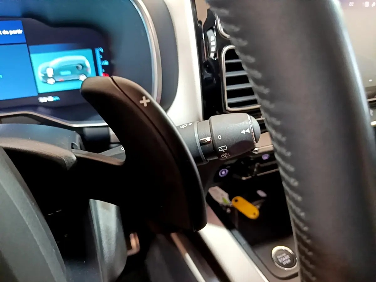 Gros plan sur la palette de changement de vitesse droite et le tableau de bord digital bleu du Citroën C5 Aircross Hybrid noir.