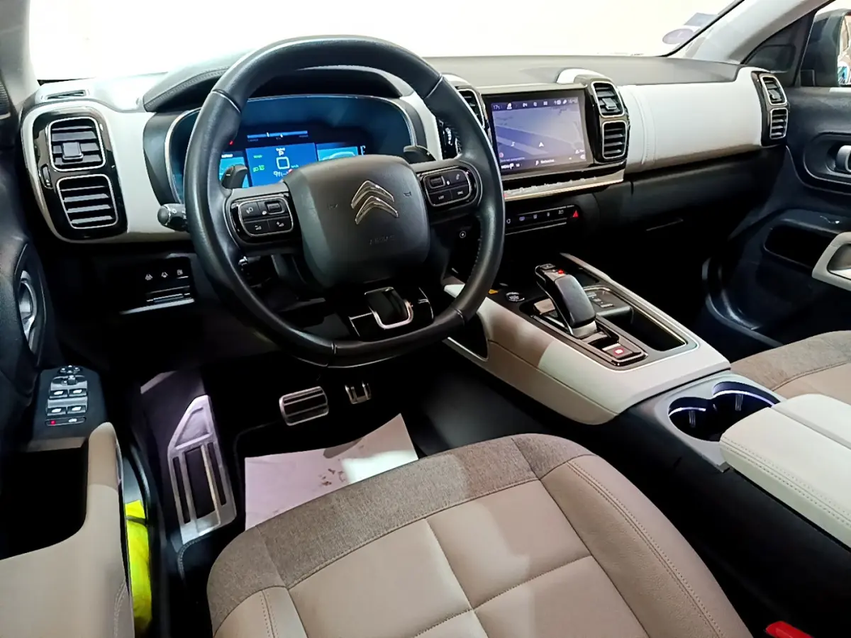 Intérieur clair du Citroën C5 Aircross Hybrid 225, vue depuis le siège conducteur sur le tableau de bord et volant cuir noir.