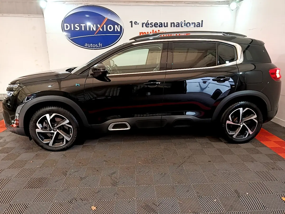 Profil côté gauche d'un Citroën C5 Aircross Hybrid 225 ë-EAT8 Shine noir, avec jantes alliage et détails chromés sur les seuils.