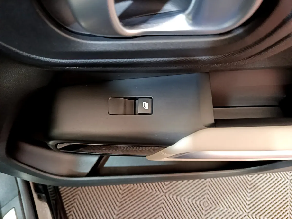 Gros plan sur le bouton de commande de la vitre côté gauche dans l'habitacle noir du Citroën C5 Aircross Hybrid 225 ë-EAT8 Shine.
