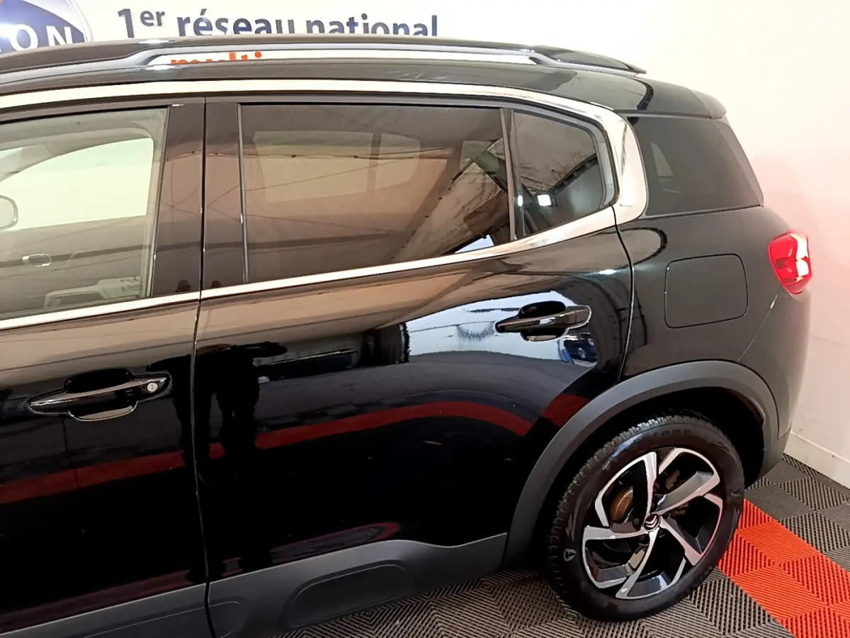 Profil côté droit noir brillant du Citroën C5 Aircross Hybrid 225 ë-EAT8 Shine avec jantes alliage et barres de toit chromées.