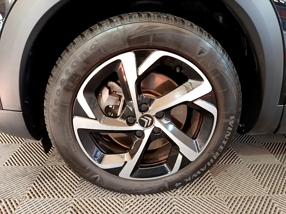 Gros plan sur la jante noire et argentée du côté avant gauche du Citroën C5 Aircross Hybrid 225 ë-EAT8 Shine noir.