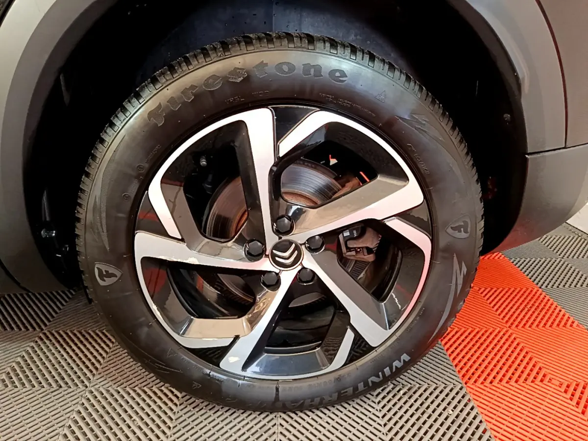 Gros plan sur la roue avant gauche du Citroën C5 Aircross Hybrid 225 ë-EAT8 Shine avec jante alliage bicolore et pneu Firestone.