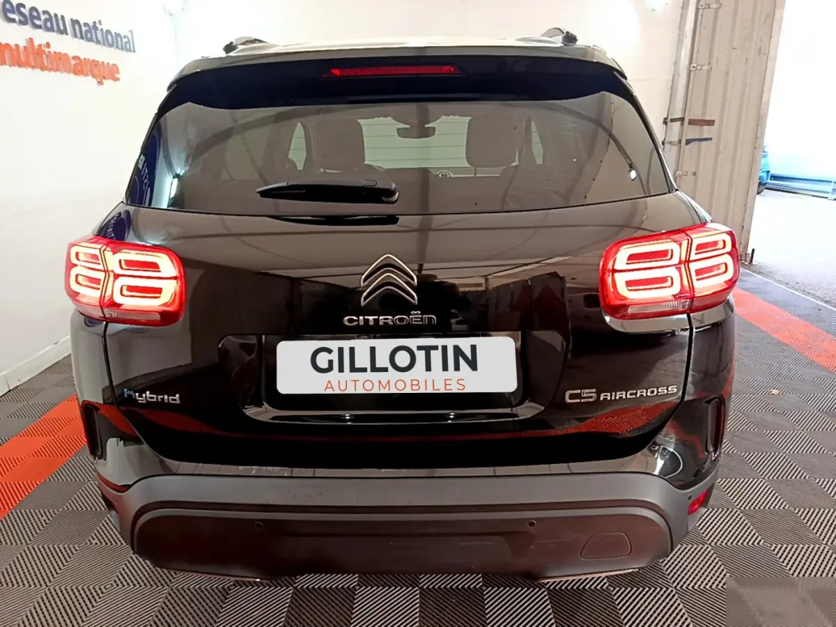 Vue arrière d'un Citroën C5 Aircross Hybrid noir avec feux arrière LED allumés et logo centré sur le hayon.