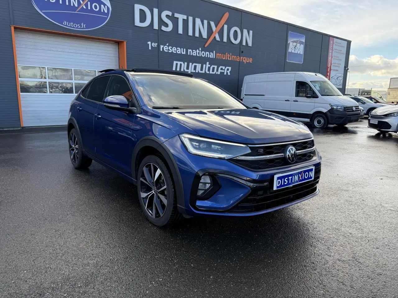 Volkswagen Taigo bleu récif métallisé en 3/4 avant droit avec jantes alliage noires brillantes et calandre R-Line.