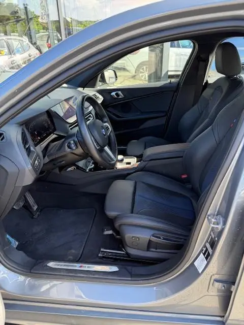 Vue intérieure côté conducteur de la BMW Série 1 118d gris foncé, avec sièges cuir et tableau de bord digital.