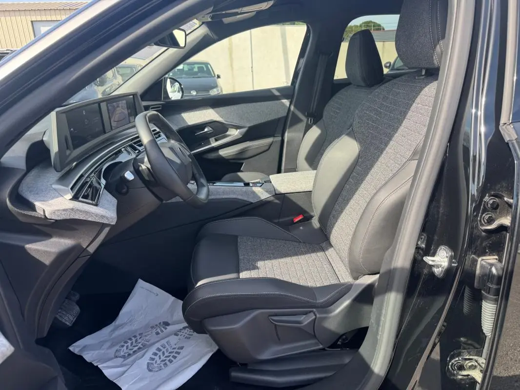 Vue intérieure côté conducteur du Peugeot 3008 Hybrid 145 Allure 2025 noir, avec sièges tissu et cuir et cockpit numérique.
