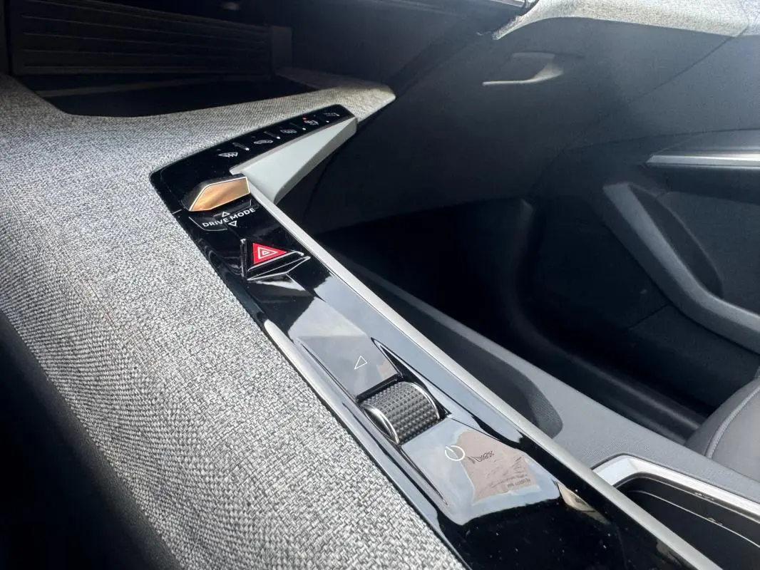 Vue intérieure rapprochée de la console centrale du Peugeot 3008 Hybrid 145 Allure 2025, avec finition tissu gris et commandes tactiles noires.