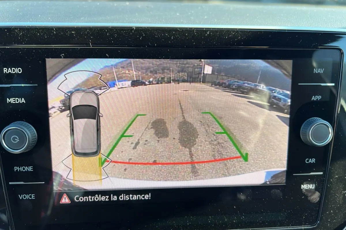 Écran caméra de recul du Volkswagen T-Cross blanc pur, affichant l'aire de stationnement avec repères verts et rouges.