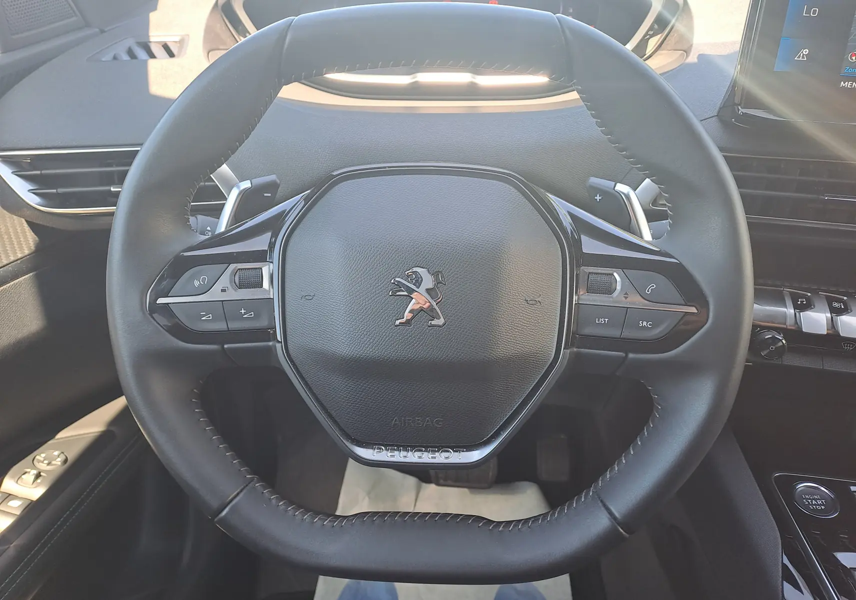 Vue rapprochée du volant cuir noir du Peugeot 3008 2023, avec commandes intégrées et logo lion central.