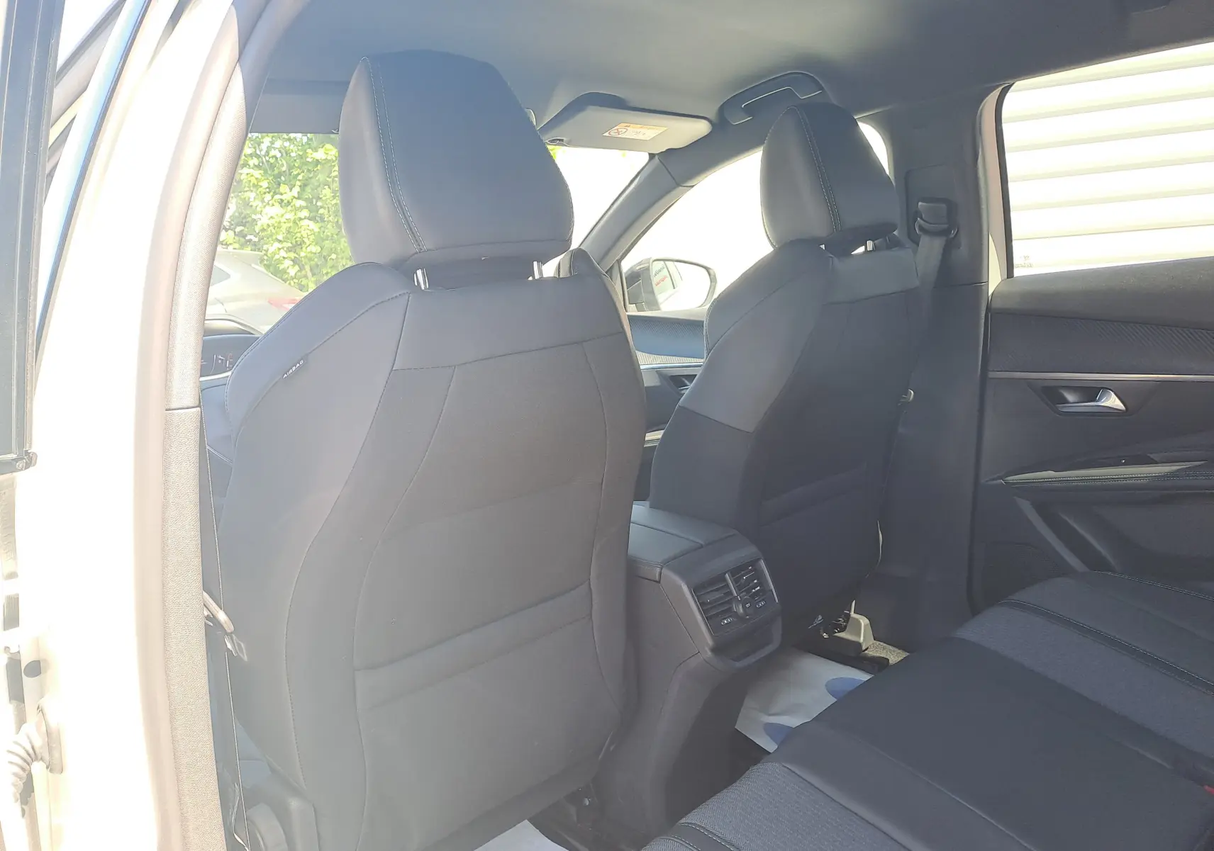 Vue intérieure arrière du Peugeot 3008 2023, sièges noirs et aérateurs centraux entre les sièges avant.