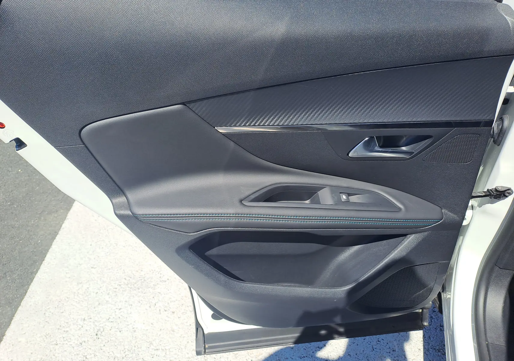 Vue rapprochée de la porte avant gauche blanche nacrée du Peugeot 3008 2023 avec intérieur noir et détails en carbone.