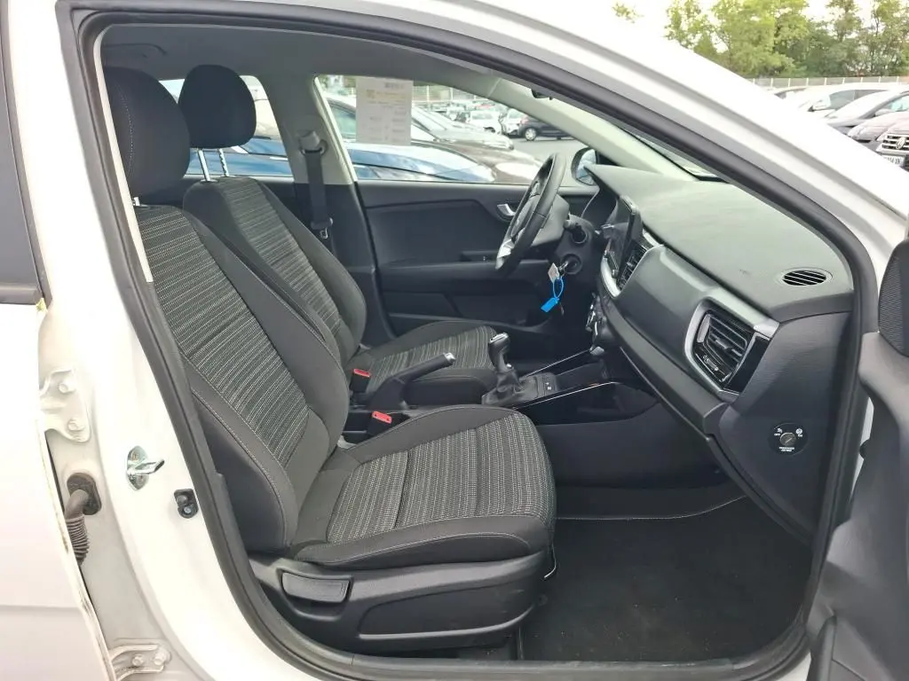 Vue intérieure côté conducteur du Kia Stonic blanc 2023, montrant les sièges avant et la console centrale avec boîte manuelle.