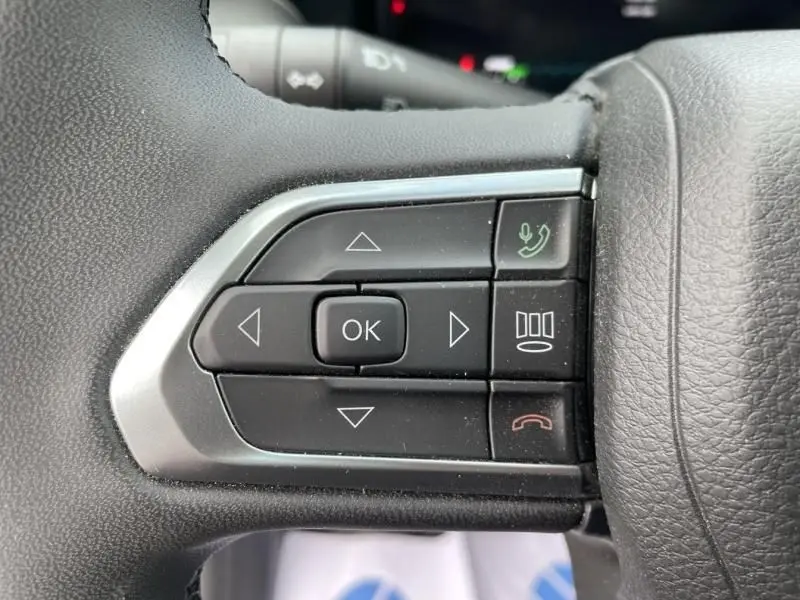 Gros plan sur les commandes au volant du Jeep Compass gris 2023, boutons multifonctions avec navigation et appel téléphonique.
